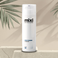 5 ounce skincare bottle labeled 'Mixi Skincare Mixi Clean cleansing gel' in a neutral backround with green leaves and on a stone surface.