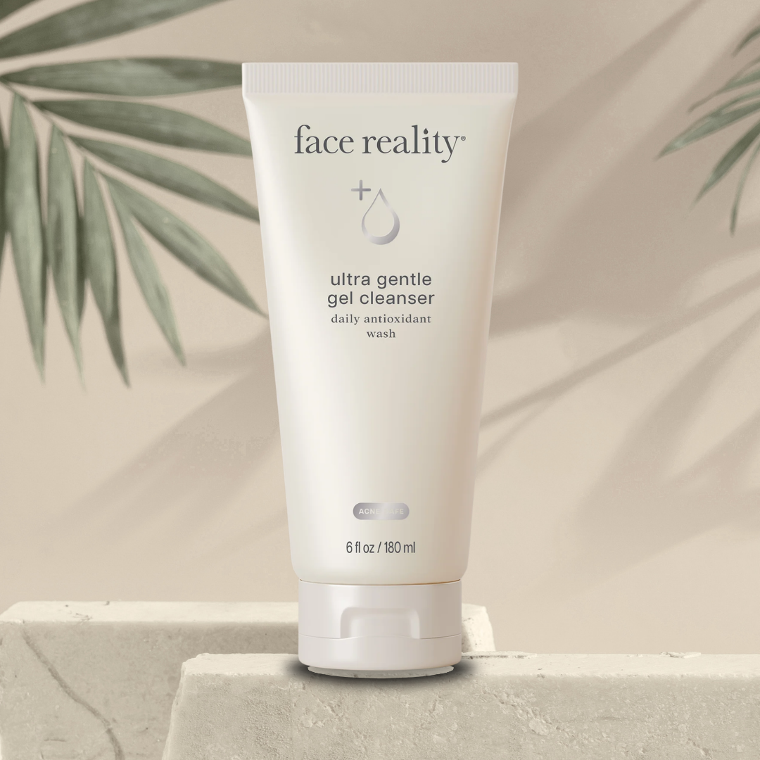 Tube of 'face reality' ultra gentle gel cleanser on a neutral background with green leaves and a stone surface.