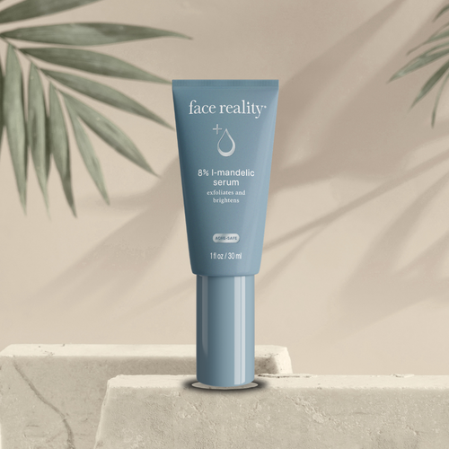 Blue skincare serum tube labeled 'face reality 8% l-mandelic serum' that 'exfoliates and brightens' on a neutral background with green leaves.